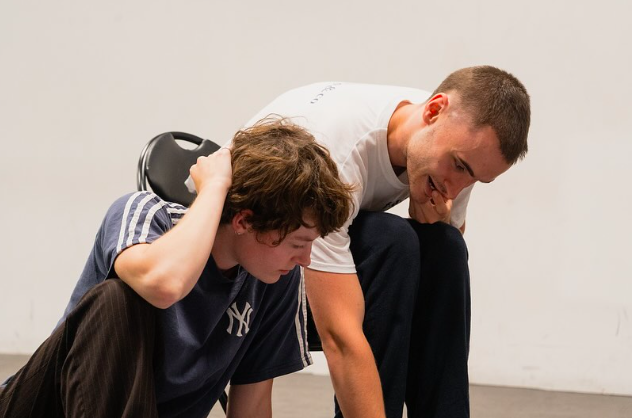 Two performers in a rehearsal room, mid-devising, physical comedy